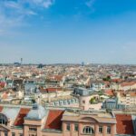 Explore Vienna's charming cityscape with this panoramic view of historic architecture and lively urban life under a clear sky.