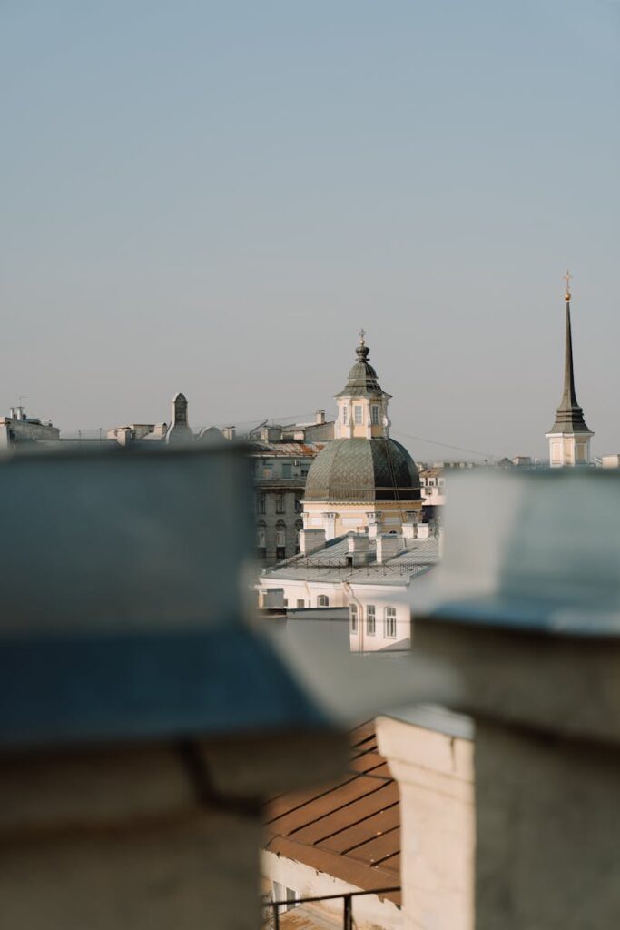 Picturesque view of an old European city's rooftops with domes and spires under a clear blue sky.