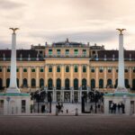 Majestic view of Schonbrunn Palace in Vienna, Austria, during sunset with people exploring the iconic landmark.