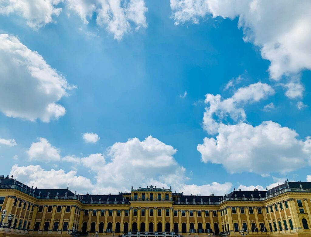 yellow concrete building under blue sky and white clouds during daytime